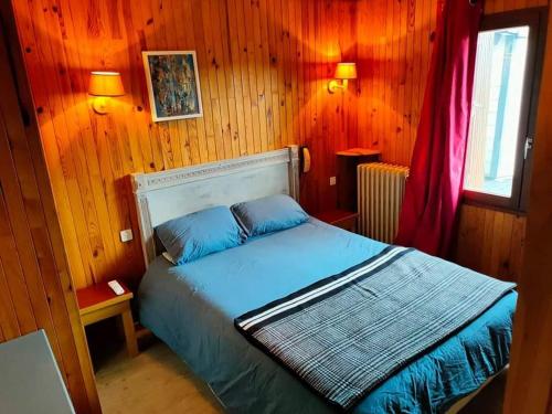 a bedroom with a bed in a wooden wall at Chalet du Mont Lozère in Cubières