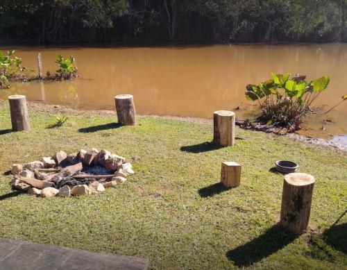 a fire pit in the grass next to a body of water at Paraíso Capitólio Suítes Pousada in Capitólio