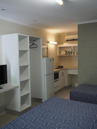 a room with a bed, a refrigerator, and a television at Sunbird Motel in Townsville