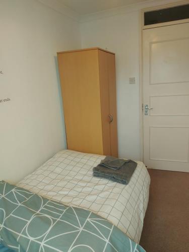 a bedroom with a bed and a wooden cabinet at Spacious and Serene Stay near Milton Keynes centre in Willen