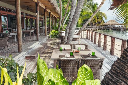 an outdoor patio with tables and chairs and a pool at Kokomo Private Island Fiji in Ndravuni