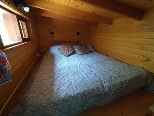 ein Schlafzimmer mit einem Bett in einer Holzhütte in der Unterkunft Hospedaje Las Gardenias in Lago Puelo