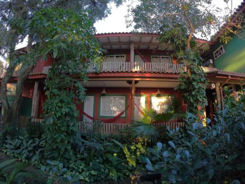 a red house with a balcony and trees at Pousada Canoa Azul na Praia da Ferrugem in Garopaba
