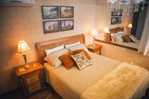 a bedroom with a bed with two lamps and a mirror at Apto Panorâmico 3 quadras da Rua Coberta in Gramado