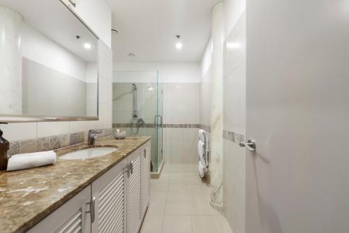 a white bathroom with a sink and a shower at Auckland Waterfront Serviced Apartments on Prince's Wharf in Auckland