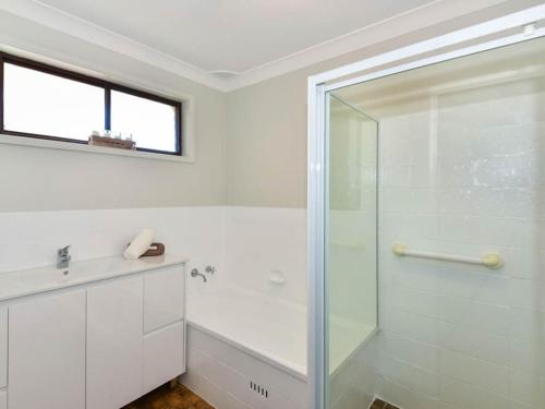 a white bathroom with a shower and a sink at Noraville Summer House in Norah Head