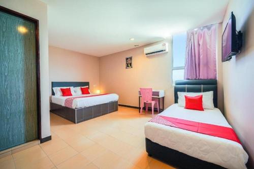 a hotel room with two beds and a table and chair at CMN Hotel & Homestay in Sungai Petani