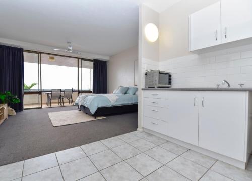 a kitchen and living room with a bed and a room with at Studio Apartment, Centre Of Airlie With Sea Views in Airlie Beach