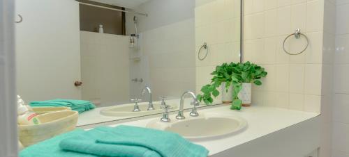 a bathroom with two sinks and a mirror at Studio Apartment, Centre Of Airlie With Sea Views in Airlie Beach