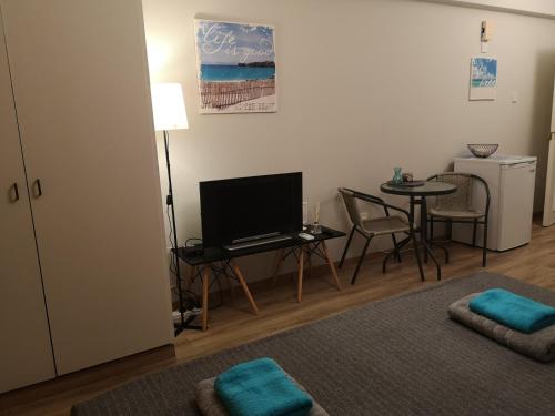 a living room with a television and a table with chairs at ANDREAS APARTMENTS in Voroklini