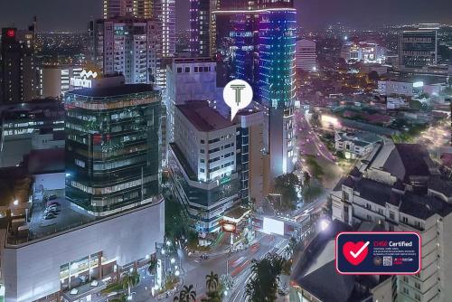 una vista de la ciudad por la noche con un cartel en Tunjungan Hotel, en Surabaya