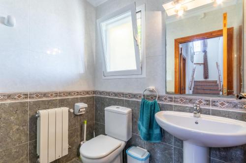 een badkamer met een toilet, een wastafel en een spiegel bij Casa Maravilla in Benitachell