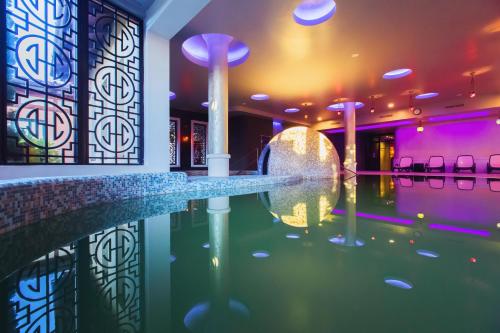 - une piscine au milieu d'une pièce avec des lumières violettes dans l'établissement Caramell Premium Resort Superior, à Bük