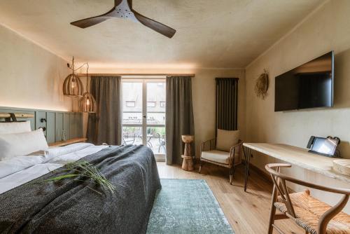 a bedroom with a bed and a television and a chair at Hotel / Weingut Meintzinger in Frickenhausen