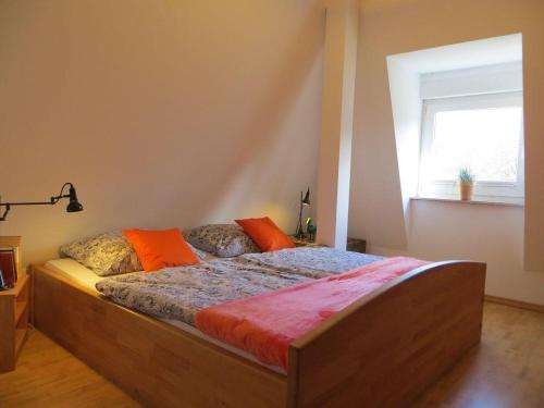 a bedroom with a bed with orange pillows and a window at Weisses-Haus-am-Kurpark-Fewo-Bergblick in Bad Suderode