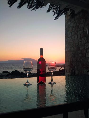 a bottle of wine and two wine glasses on a table at Kyanis Villa , Karpathos Afiartis in Afiartis