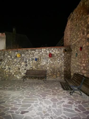 two benches sitting in front of a stone wall at Casa Dema climatizzata con wifi in Martis