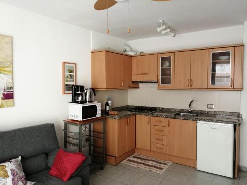 una cucina con armadi in legno e un divano in camera di Cande a Guía de Isora