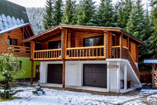 a log home with a deck and garage at Pensiunea Vanatorul in Obarsia-Lotrului