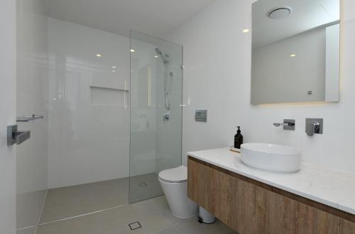 a bathroom with a shower and a sink and a toilet at X Kirra Apartments in Gold Coast