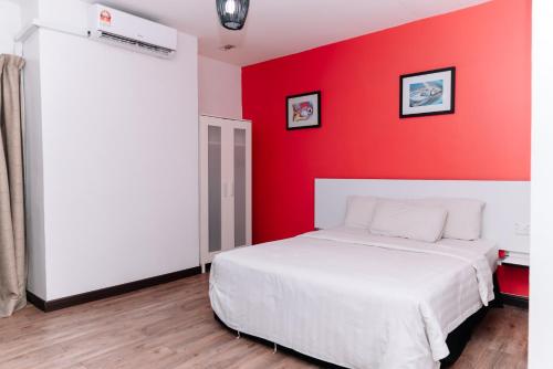 a bedroom with a red wall and a white bed at Ridel Sunset Hotel in Kota Bharu