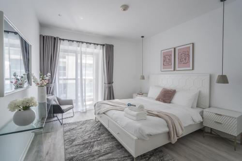 a white bedroom with a bed and a window at HiGuests - Cloudy Apt, 10-min walk to Dubai Harbor in Dubai