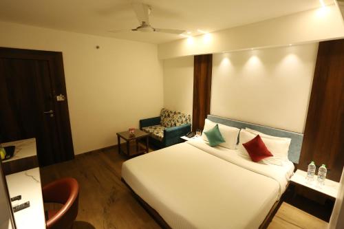 a hotel room with a bed and a chair at Alba Premier, Indore in Indore