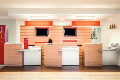 a woman sitting at a counter in a kitchen at Hotel Ibis Milano Malpensa in Cardano al Campo
