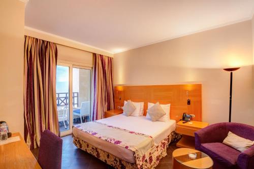 um quarto de hotel com uma cama e uma cadeira em Porto El Jabal Hotel em Ain Sokhna