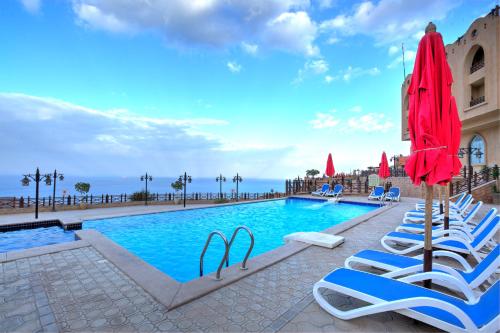 アインソフナにあるPorto El Jabal Hotelのラウンジチェアとパラソル付きのスイミングプール