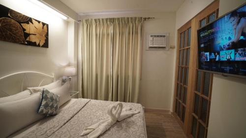a hotel room with a bed and a tv at 1775 Adriatico Suites in Manila