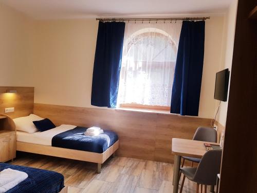 1 dormitorio con 1 cama y una ventana con cortinas azules en Gościniec Piast Hotel i Camping, en Brzeźno