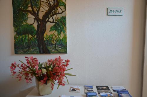 a vase of flowers on a table with a painting at Hotel Delle Isole in La Maddalena