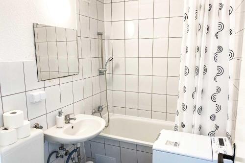 a white bathroom with a sink and a bath tub at City-Apartment Halle mit TV und WLAN in Angersdorf