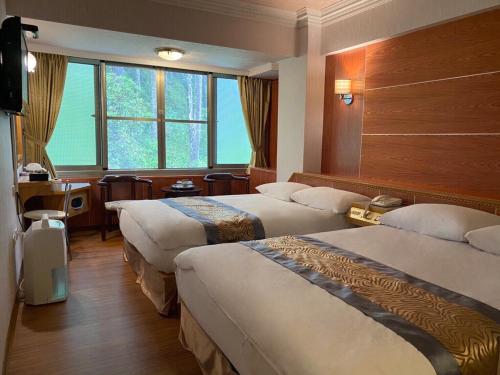 中正区にあるKao Feng Hotelのベッド3台と窓が備わるホテルルームです。