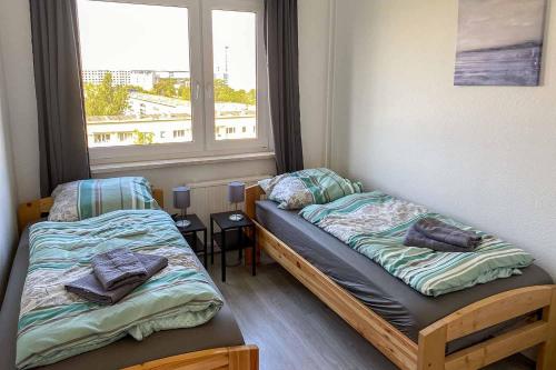 2 camas individuais num quarto com uma janela em City-Apartment Halle mit TV und WLAN em Angersdorf