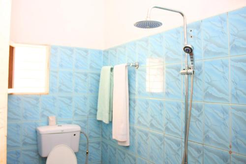 a blue tiled bathroom with a shower and a toilet at Bilkon Hotel Jinja in Jinja