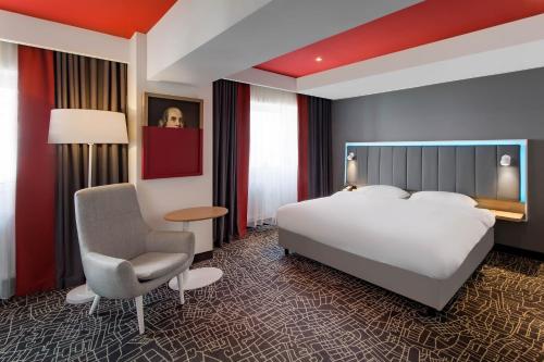 a hotel room with a bed and a chair at Park Inn by Radisson Bucharest Hotel & Residence in Bucharest