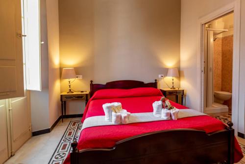 a bedroom with a red bed with two towels at Domo Sa Barra in SantʼAntìoco