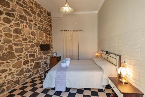 a bedroom with a bed and a stone wall at Domo Sa Barra in SantʼAntìoco