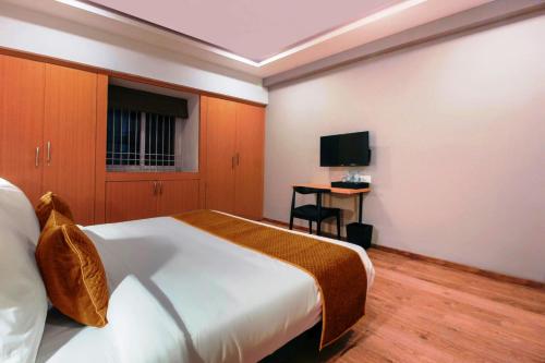 a bedroom with a bed and a desk with a television at Hotel Mallikarjuna Residency in Hyderabad