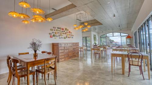 a dining room with tables and chairs and windows at Socalco Nature Calheta in Calheta