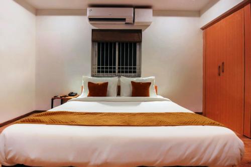 a bedroom with a large white bed with orange blanket at Hotel Mallikarjuna Residency in Hyderabad