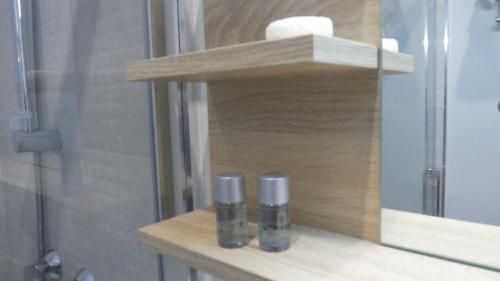a bathroom with a shelf with two bottles on it at Plaza Pombo B&B - Hostal in Santander