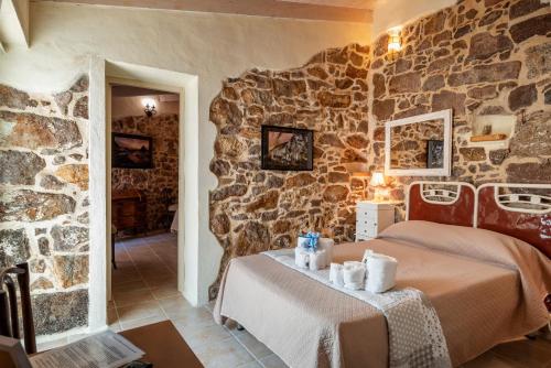 a bedroom with two beds and a stone wall at Domo Sa Barra in SantʼAntìoco