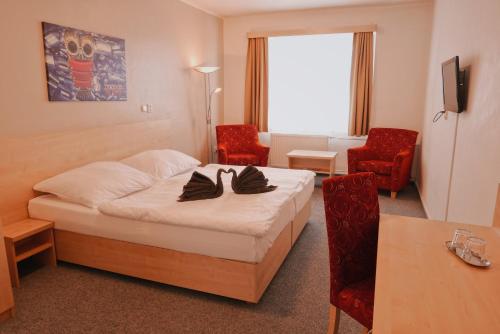 ein Hotelzimmer mit einem Bett und zwei Stühlen in der Unterkunft Městský hotel Bobík in Volary