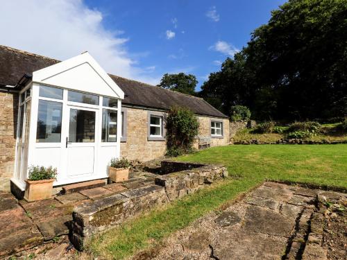 a cottage with a white door and a yard at Allergarth Barn in Carlisle