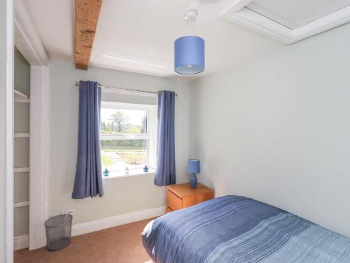 a bedroom with a blue bed and a window at Allergarth Barn in Carlisle