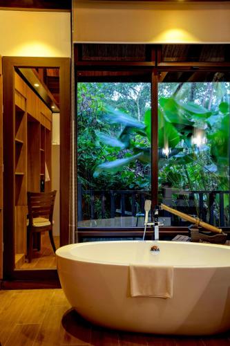 a bath tub in a bathroom with a large window at Lihim Resorts in El Nido