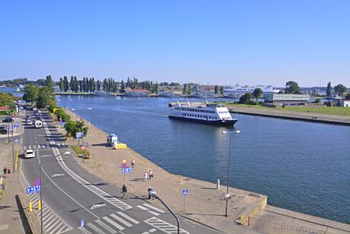 a boat on a river with a road and a street at Villa Concha-Apartamenty Bryza-Parking in Świnoujście